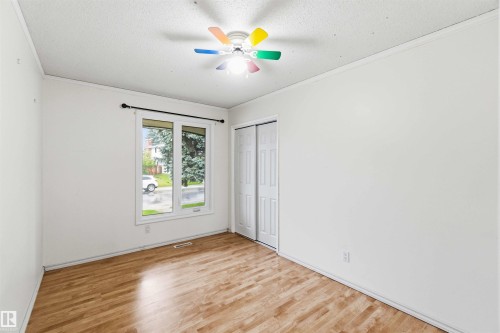 Room featuring wood-finish flooring, a double-pane window, and a ceiling fan with integrated lighting - 17303 107 Street, Edmonton, AB 