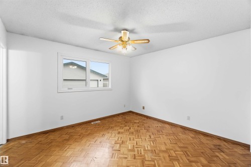Room featuring wood-finish parquet flooring, white walls, and a white ceiling with a ceiling fan - 17303 107 Street, Edmonton, AB 