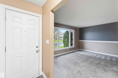 Entry foyer with a paneled white door, showcasing a gray tiled threshold and neutral wall tones - 17303 107 Street, Edmonton, AB 
