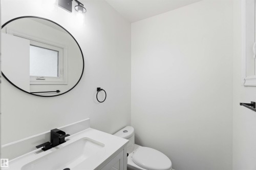 Vanity area featuring a round mirror, white countertop, and black fixtures - 17303 107 Street, Edmonton, AB 