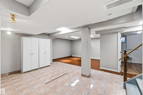 Spacious lower-level area featuring light-toned tile flooring, recessed lighting, support columns, and built-in storage cabinetry - 17303 107 Street, Edmonton, AB 