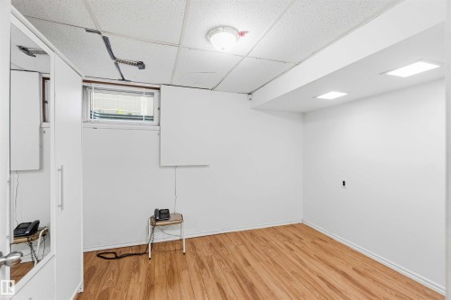 Bright room featuring wood-finish flooring, white walls, and a drop ceiling with recessed lighting - 17303 107 Street, Edmonton, AB 