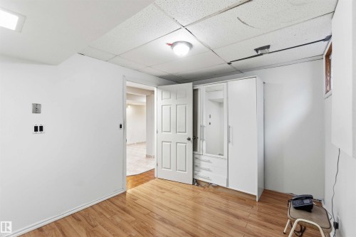 Room featuring wood-finish flooring, white walls, and a drop ceiling with integrated lighting - 17303 107 Street, Edmonton, AB 