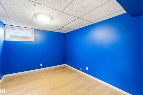Room featuring wood-finish flooring, a drop ceiling, and a single window with white trim - 17303 107 Street, Edmonton, AB 