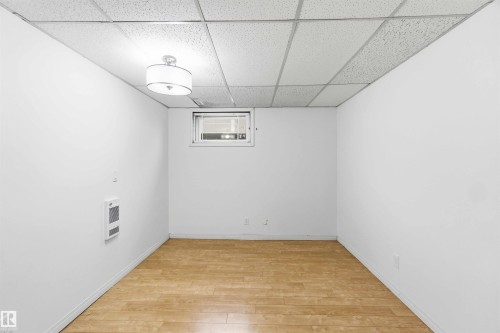 Versatile room featuring light-toned wood-finish flooring, white walls, and a dropped ceiling with integrated lighting - 17303 107 Street, Edmonton, AB 