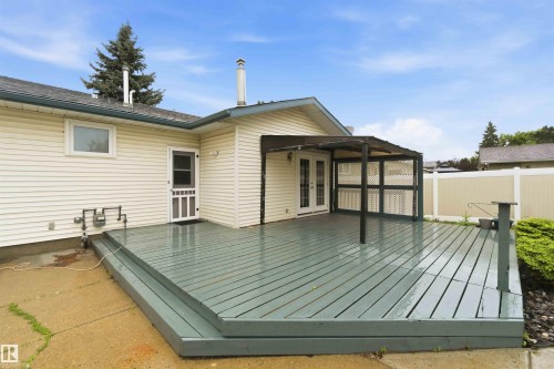 Expansive wood deck with a built-in pergola, offering direct access to the interior via double French doors and a secondary exterior door - 17303 107 Street, Edmonton, AB 