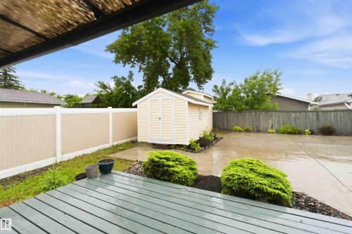 Expansive concrete patio with a storage shed, wood-finish decking, and perimeter landscaping - 17303 107 Street, Edmonton, AB 