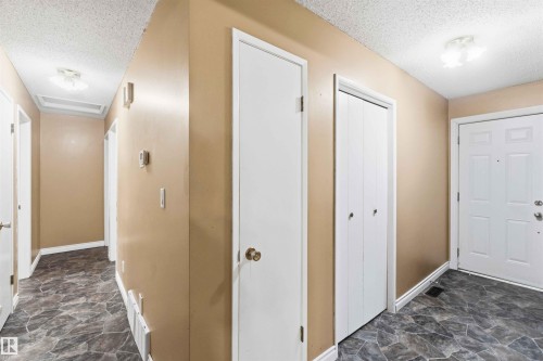 Foyer featuring panel-style entry door, textured ceiling, and dark patterned flooring - 17303 107 Street, Edmonton, AB 