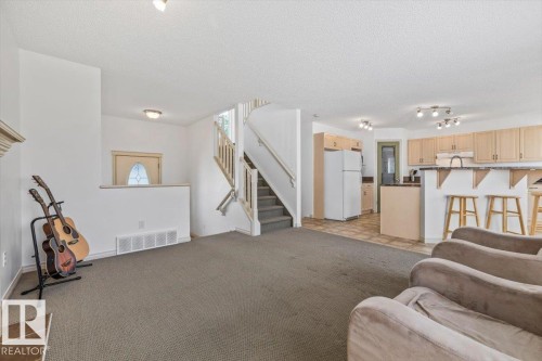 Open-concept living area featuring a kitchen with light wood cabinetry, a breakfast bar, and integrated appliances - 8509 7 Avenue, Edmonton, AB 