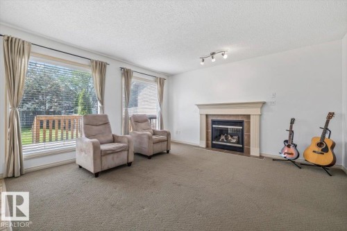 Living space featuring a fireplace with a mantel, track lighting, and expansive windows - 8509 7 Avenue, Edmonton, AB 