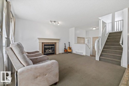 Living area featuring a fireplace with a light-colored mantel and brick surround - 8509 7 Avenue, Edmonton, AB 