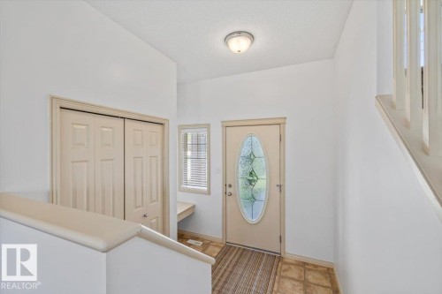 Entryway featuring a decorative oval glass front door and a built-in bench - 8509 7 Avenue, Edmonton, AB 
