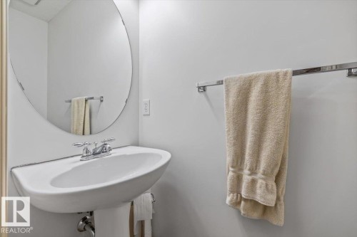 Pedestal sink with chrome-finish faucet and an oval wall mirror - 8509 7 Avenue, Edmonton, AB 