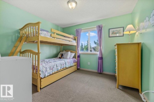 Room featuring a window with purple drapes, light green walls, and neutral-toned carpeting - 8509 7 Avenue, Edmonton, AB 