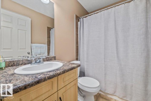Bathroom featuring a light wood-finish vanity with a dark speckled countertop and an undermount sink - 8509 7 Avenue, Edmonton, AB 