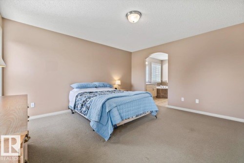 Spacious room featuring neutral-toned walls, textured ceiling, and carpet flooring - 8509 7 Avenue, Edmonton, AB 