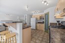 Kitchen featuring light wood-finish cabinetry, track lighting, and a textured countertop - 8509 7 Avenue, Edmonton, AB 