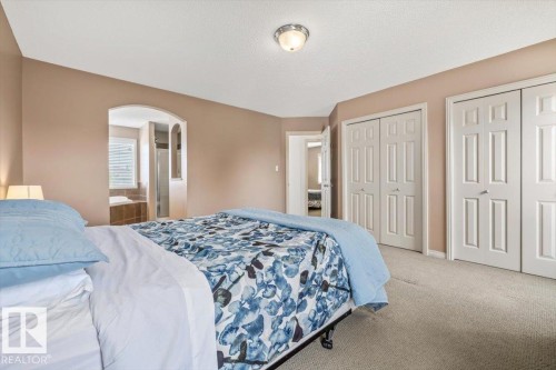 Carpeted bedroom featuring neutral-toned walls, white trim, and a semi-flush mount ceiling fixture - 8509 7 Avenue, Edmonton, AB 
