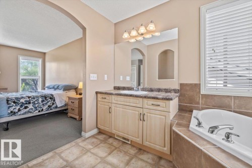 Bathroom vanity featuring a single sink, an integrated countertop, and cabinetry with dark hardware - 8509 7 Avenue, Edmonton, AB 