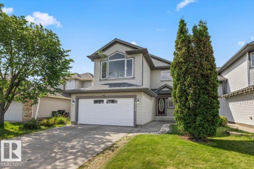Two-story residence featuring light gray siding, an attached double-bay garage, and a concrete driveway - 8509 7 Avenue, Edmonton, AB 