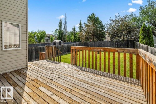Spacious wood deck with railing and stairs leading to a fully fenced backyard - 8509 7 Avenue, Edmonton, AB 