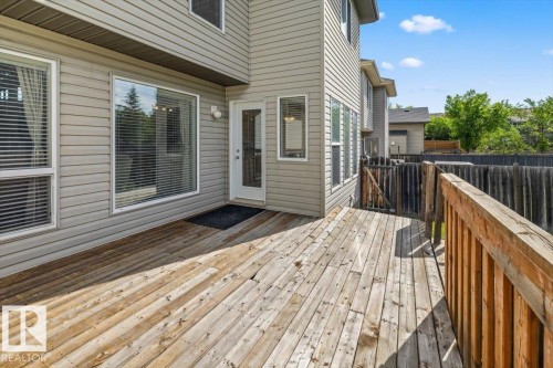 Expansive wooden deck with a wooden railing and gate, offering direct access to the interior via a white door - 8509 7 Avenue, Edmonton, AB 