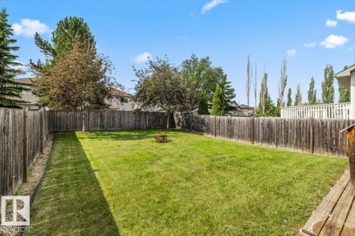 Spacious backyard with a large grassy area, mature trees, and a full perimeter fence - 8509 7 Avenue, Edmonton, AB 