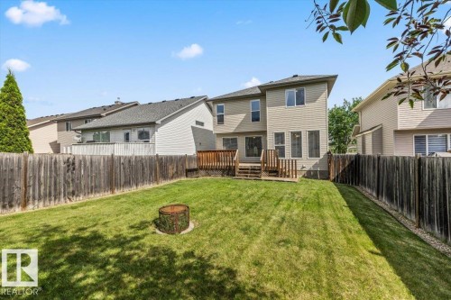 Spacious backyard featuring a manicured lawn, a two-level wood deck, and full privacy fencing - 8509 7 Avenue, Edmonton, AB 