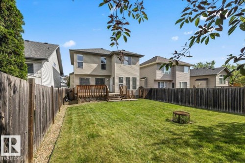 Spacious backyard featuring a manicured lawn, a two-story residence with siding, and a multi-level wooden deck - 8509 7 Avenue, Edmonton, AB 
