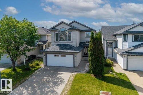 Contemporary two-story residence featuring a two-car garage with white doors, a concrete driveway, and an arched entry door - 8509 7 Avenue, Edmonton, AB 