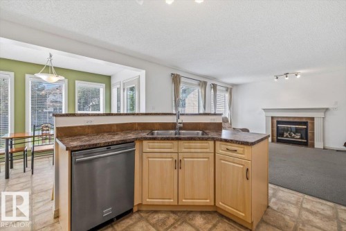 Kitchen peninsula featuring a double basin stainless steel sink and integrated dishwasher - 8509 7 Avenue, Edmonton, AB 