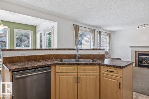 Kitchen with light wood cabinetry, stainless steel sink, and stainless steel dishwasher - 8509 7 Avenue, Edmonton, AB 