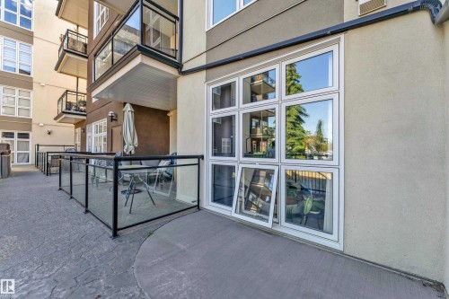 Ground-level patio featuring a glass railing and stamped concrete flooring - 129 10407 122 Street, Edmonton, AB 