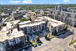 Modern multi-story building featuring multiple balconies, a structured parking area, and mature landscaping - 