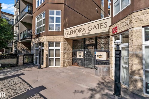 Building exterior featuring a stone facade and dark stucco, with a prominent entry gate - 129 10407 122 Street, Edmonton, AB 