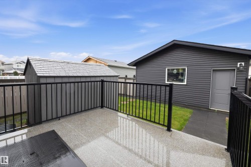 Spacious deck with black metal railings, featuring a textured concrete surface - 6084 179 Avenue, Edmonton, AB 