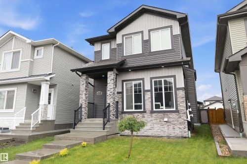 Contemporary two-story exterior featuring a multi-tone facade with dark gray siding, light gray paneling, and a stone-clad lower level - 6084 179 Avenue, Edmonton, AB 