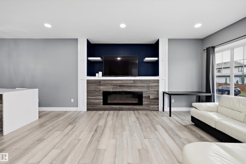 Living area featuring wood-finish flooring, recessed lighting, and a built-in media center with an electric fireplace - 6084 179 Avenue, Edmonton, AB 
