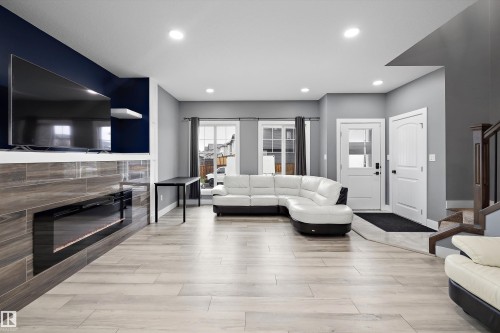 Spacious living area featuring light wood-finish flooring, recessed lighting, and a contemporary fireplace with tile surround - 6084 179 Avenue, Edmonton, AB 