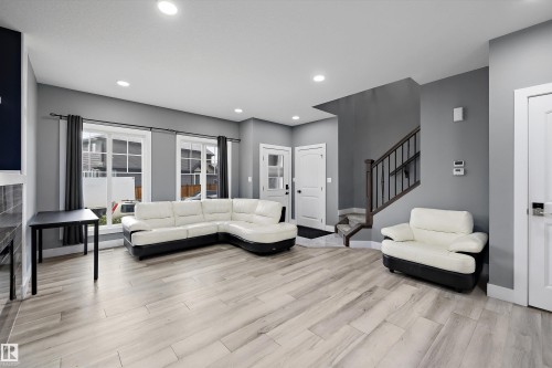 Spacious living area featuring light wood-finish flooring, recessed lighting, and multiple windows with white trim - 6084 179 Avenue, Edmonton, AB 
