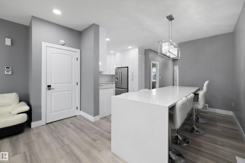 Open-concept kitchen and dining area featuring a quartz countertop island, recessed lighting, and wood-finish flooring - 6084 179 Avenue, Edmonton, AB 