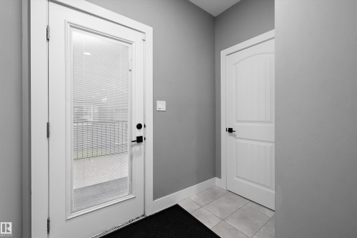 Entryway featuring a full-light door with integrated blinds, matte black hardware, tile flooring, and white baseboards - 6084 179 Avenue, Edmonton, AB 