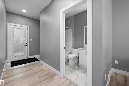 Entryway featuring wood-finish flooring, a full-lite exterior door with privacy blinds, and recessed lighting - 6084 179 Avenue, Edmonton, AB 