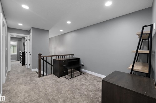 Carpeted landing featuring recessed lighting, gray wall paint, and a dark wood-finish railing with black balusters - 6084 179 Avenue, Edmonton, AB 