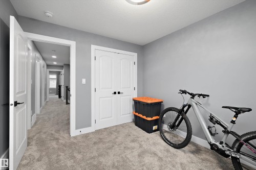 Carpeted room with light gray walls, white trim, and a double closet with black hardware - 6084 179 Avenue, Edmonton, AB 