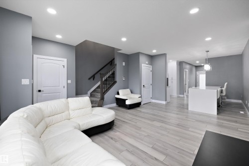 Spacious living area featuring contemporary gray wall tones and light wood-finish flooring - 6084 179 Avenue, Edmonton, AB 