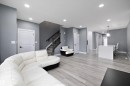Spacious living area featuring contemporary gray wall tones and light wood-finish flooring - 6084 179 Avenue, Edmonton, AB 