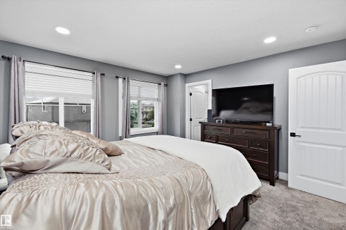 Recessed lighting illuminates the space, featuring soft grey walls and two windows with white blinds - 6084 179 Avenue, Edmonton, AB 