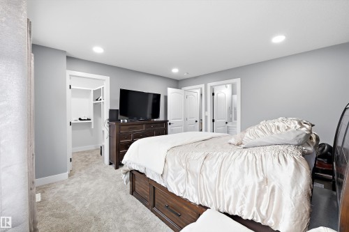 Carpeted room featuring recessed lighting, a built-in closet with shelving, two paneled doors, and light gray walls - 6084 179 Avenue, Edmonton, AB 