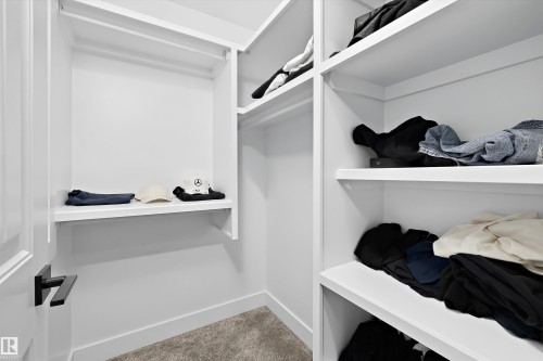 Built-in closet system with multiple white shelving units and hanging rods, complemented by a soft carpet flooring - 6084 179 Avenue, Edmonton, AB 